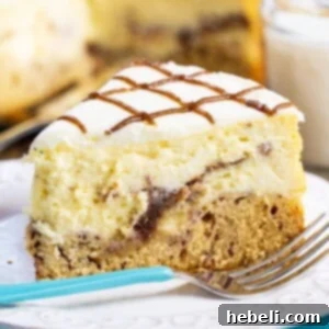 Cinnamon Swirl Cheesecake 5 A slice of Cinnamon Roll Cheesecake, ready to be enjoyed, served on a plate with a fork beside it.