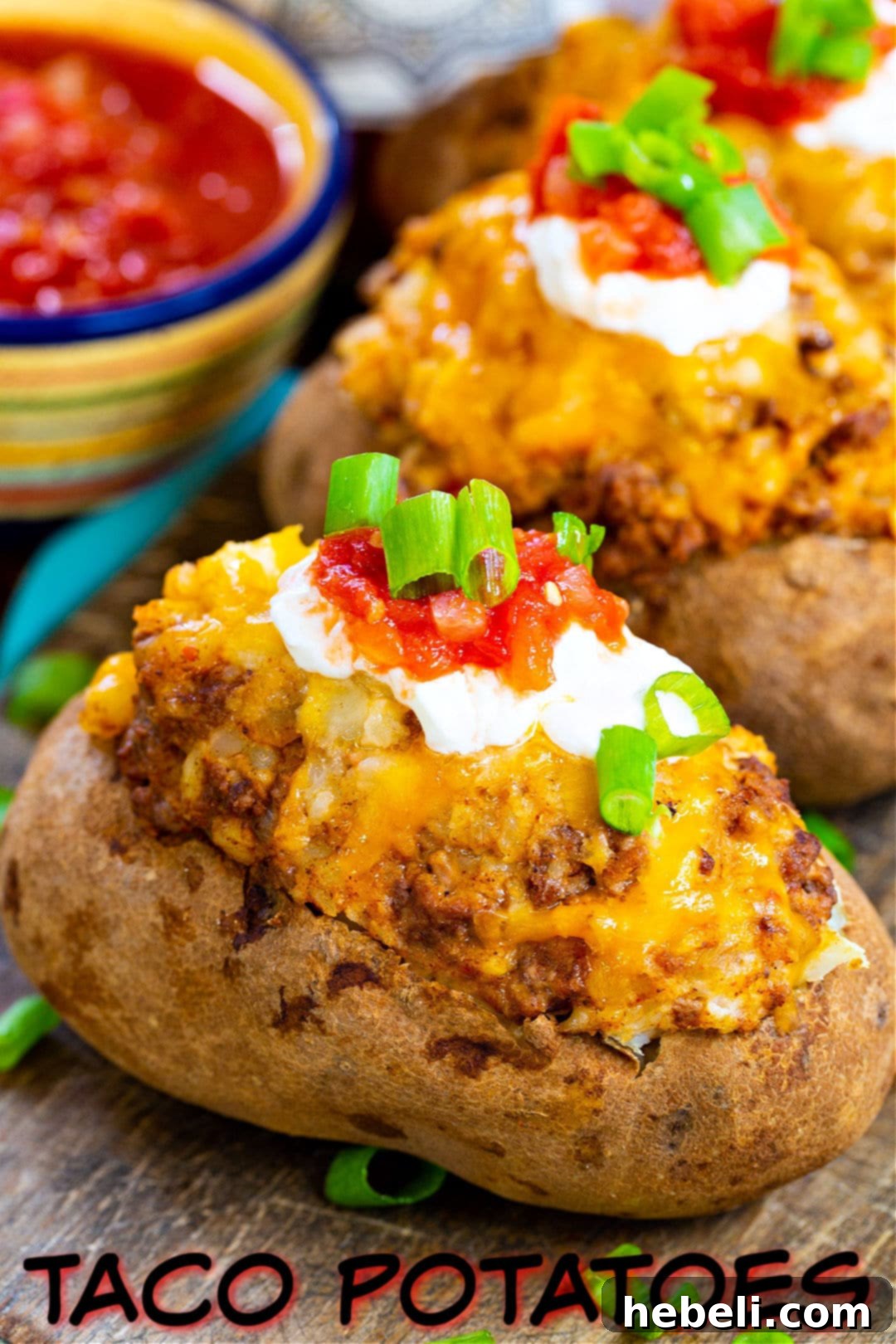 Double Stuffed Taco Potatoes on a wood cutting board, garnished and ready to serve.