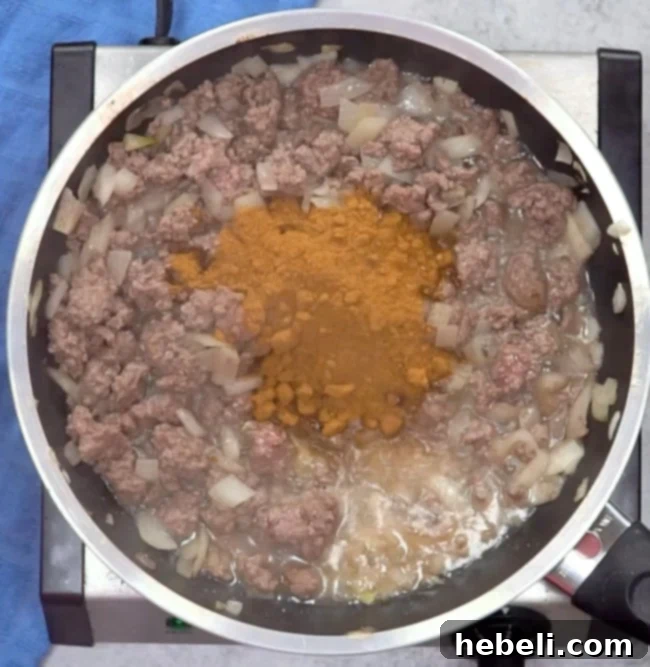 Adding taco seasoning to the ground beef mixture.