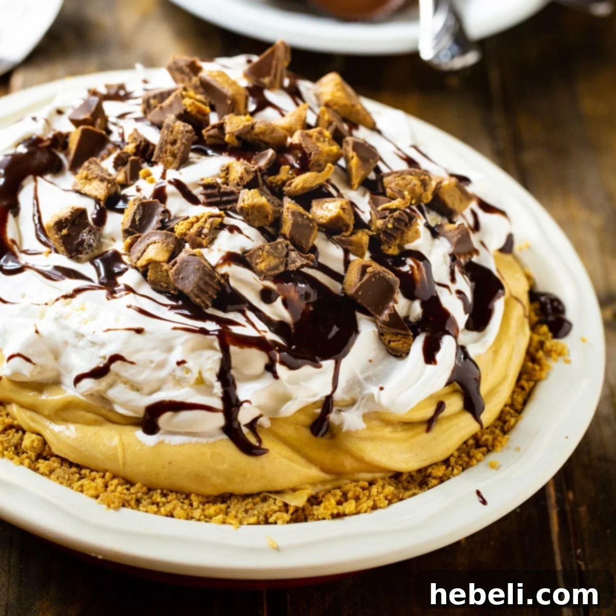 A whole Peanut Butter Pie resting in a glass pie plate, featuring a smooth, light brown filling and a golden graham cracker crust, ready to be sliced.