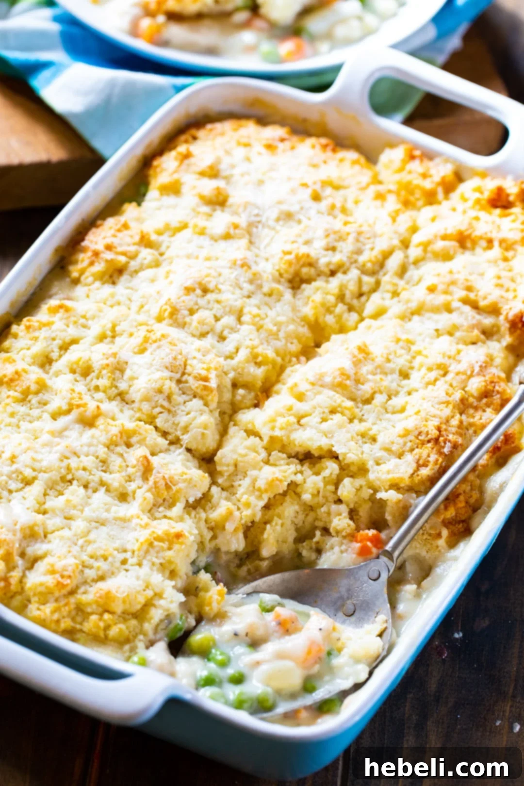 A serving of Chicken Pot Pie with Biscuit Topping being scooped from the baking dish.