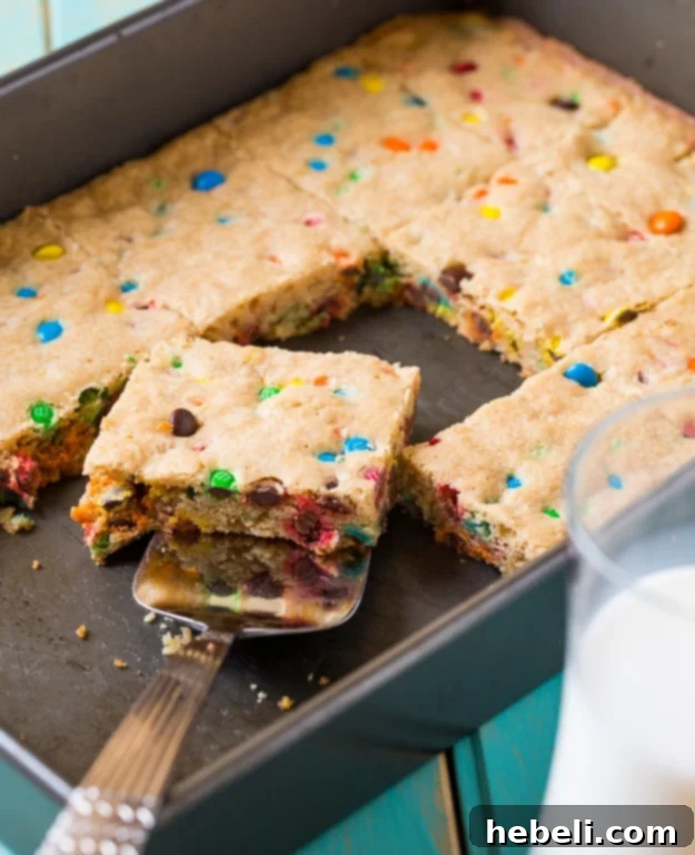 A stack of M&M Blondies on a white plate, ready to be served