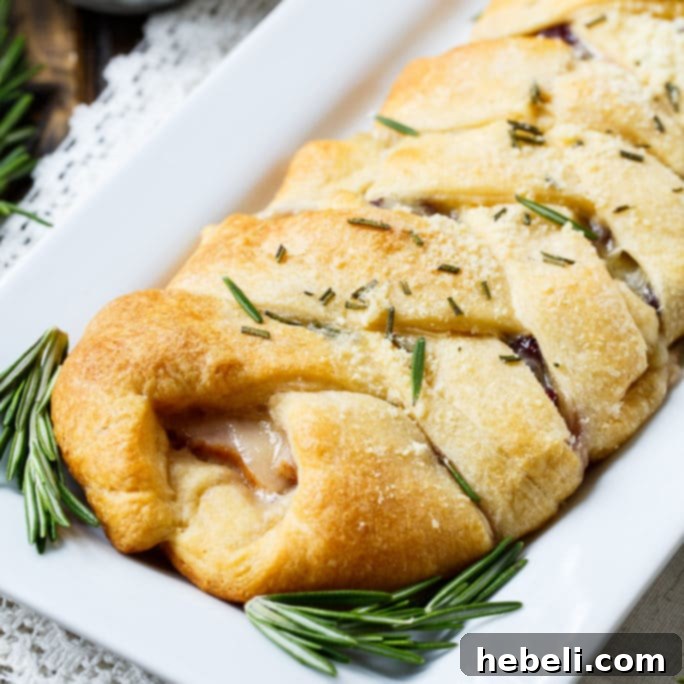 Festive Turkey Cranberry Brie Crescent Braid 2 Turkey, Cranberry, and Brie Crescent Braid, golden brown and garnished with fresh herbs, ready to be served