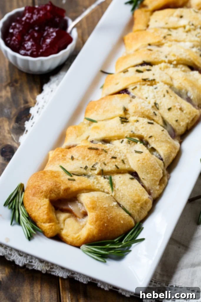 Festive Turkey Cranberry Brie Crescent Braid 5 A close-up of a beautifully braided Turkey, Cranberry, and Brie Crescent Braid, glistening and ready to be sliced