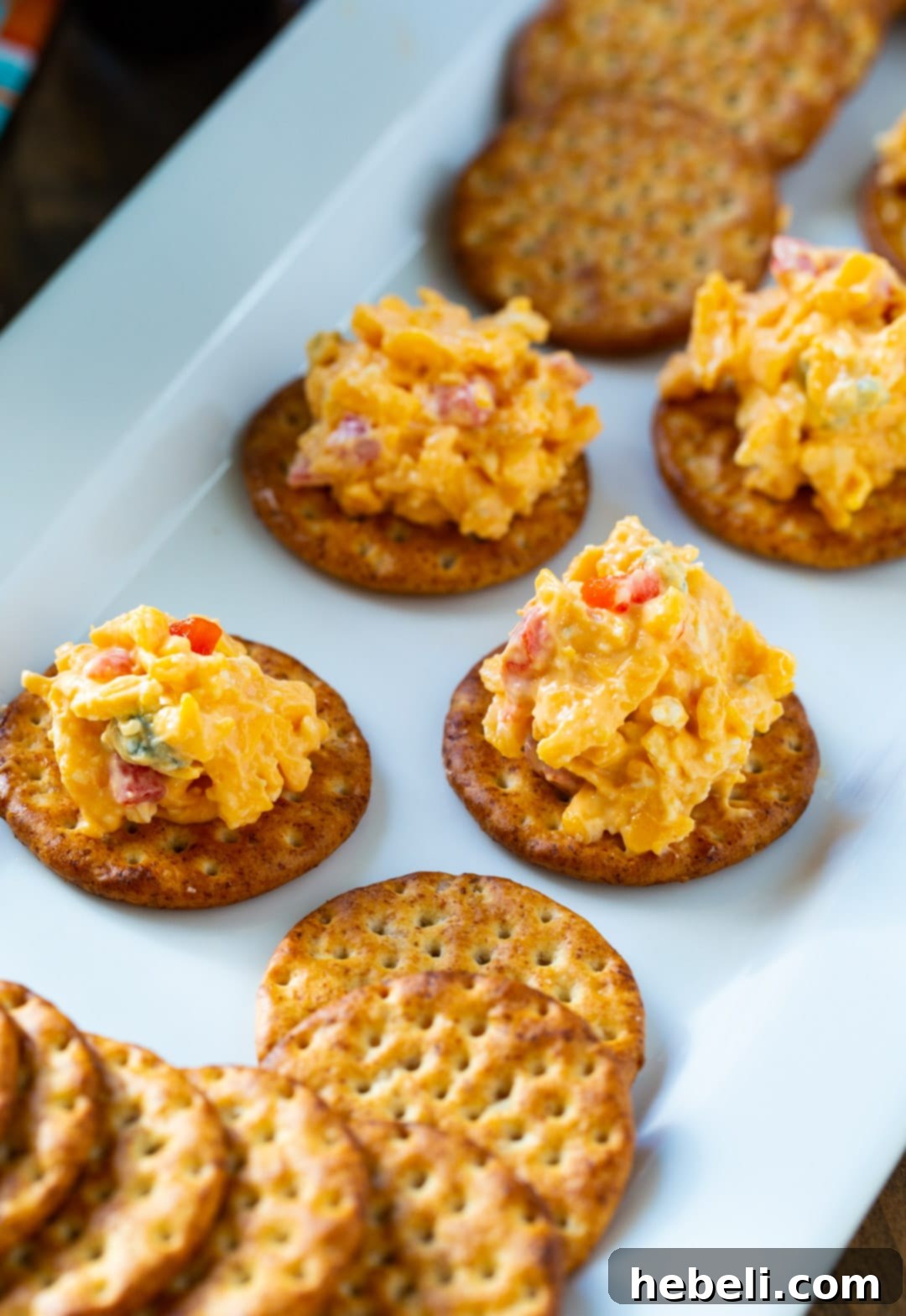Kickin' Buffalo Pimento Spread 4 Buffalo Pimento Cheese generously spread on several crackers, showcasing its tempting texture and vibrant color.
