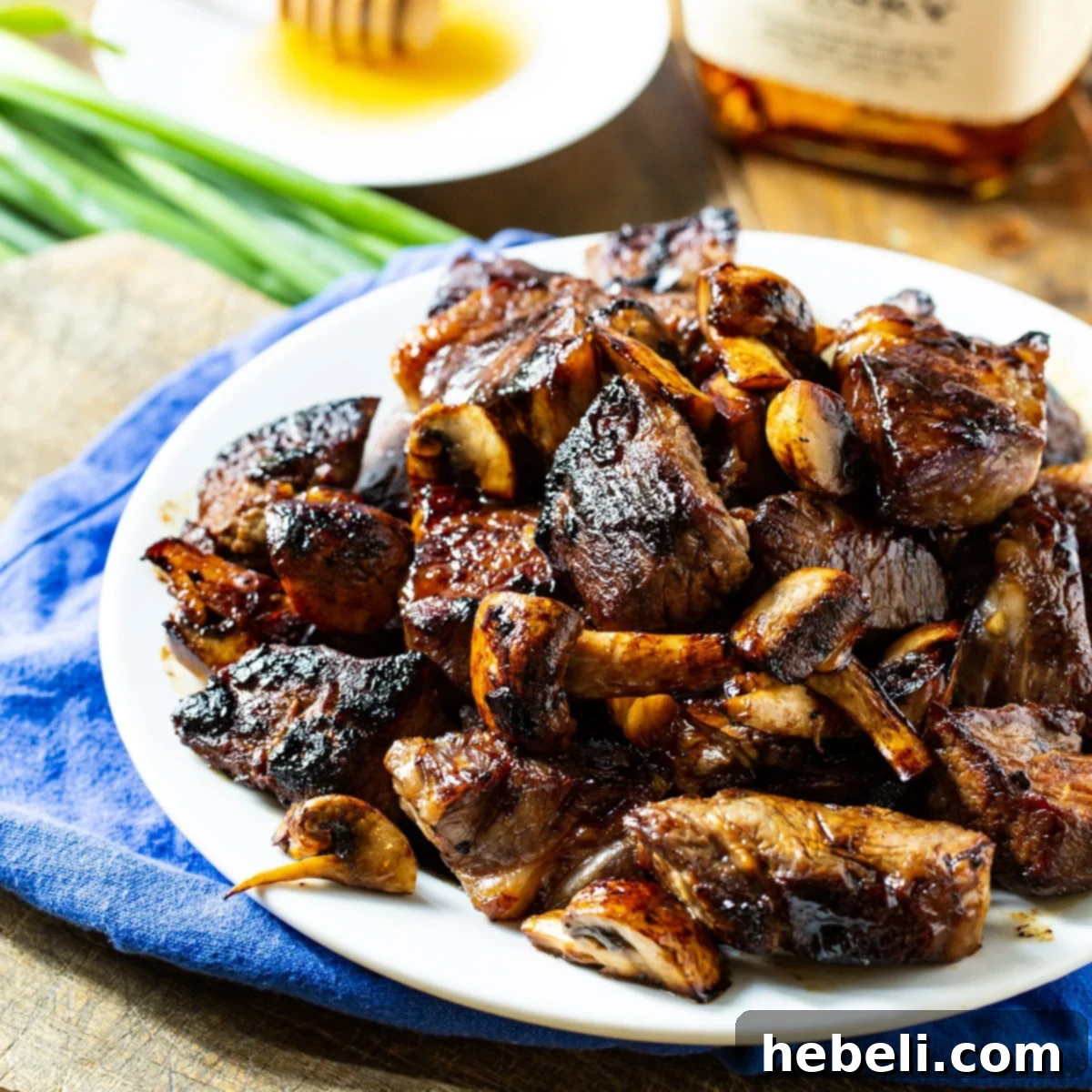 Honey Bourbon Steak Tips on a plate, garnished and ready to serve.