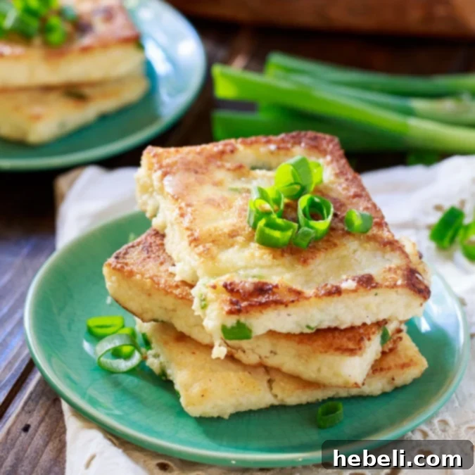 Creamy Mascarpone Grit Cakes 2 Golden brown Mascarpone Grit Cakes stacked on a plate, garnished with fresh herbs