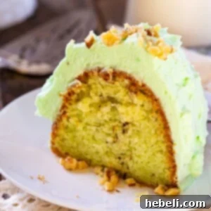 A delicious slice of Watergate Cake with its characteristic green color and fluffy frosting, garnished with chopped walnuts.