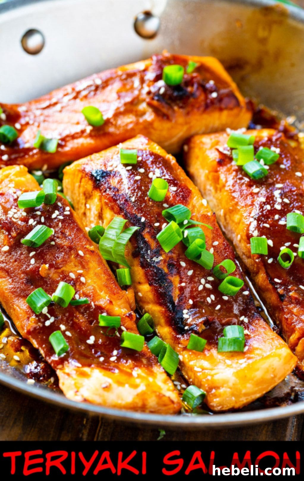 Three Teriyaki Salmon fillets in a stainless steel pan, glistening with sauce and ready to be served.