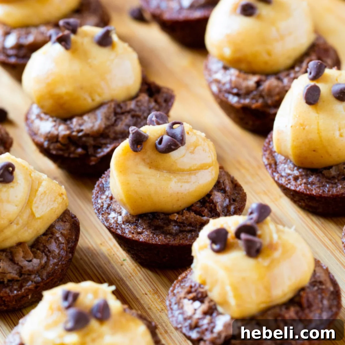 Decadent Peanut Butter Brownie Bites 2 A tray of beautifully arranged Peanut Butter Brownie Cups, showcasing their rich brownie base and creamy peanut butter topping, garnished with mini chocolate chips, set on a rustic wood board.