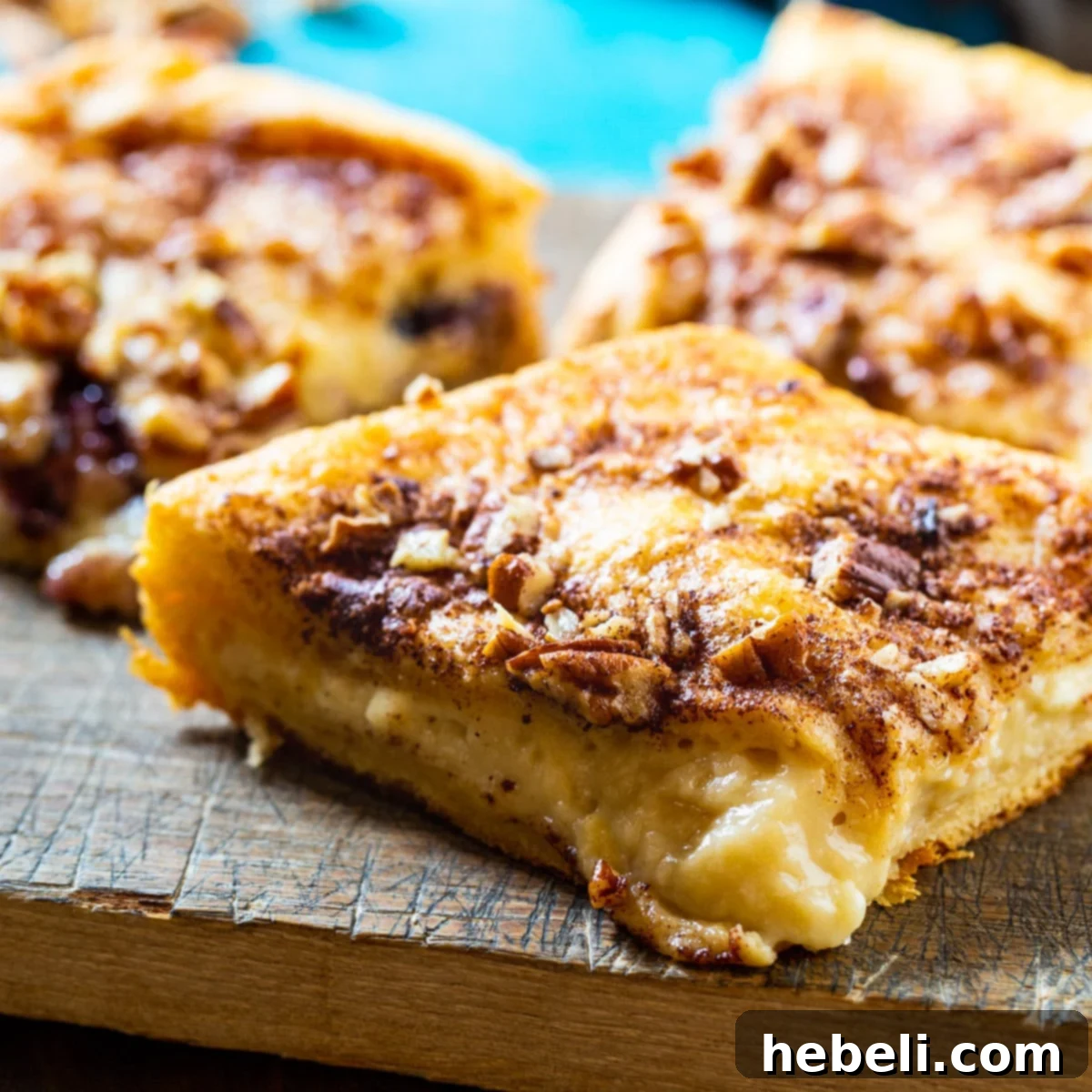 Close-up of golden brown Cream Cheese Crescent Danishes on a wooden board.