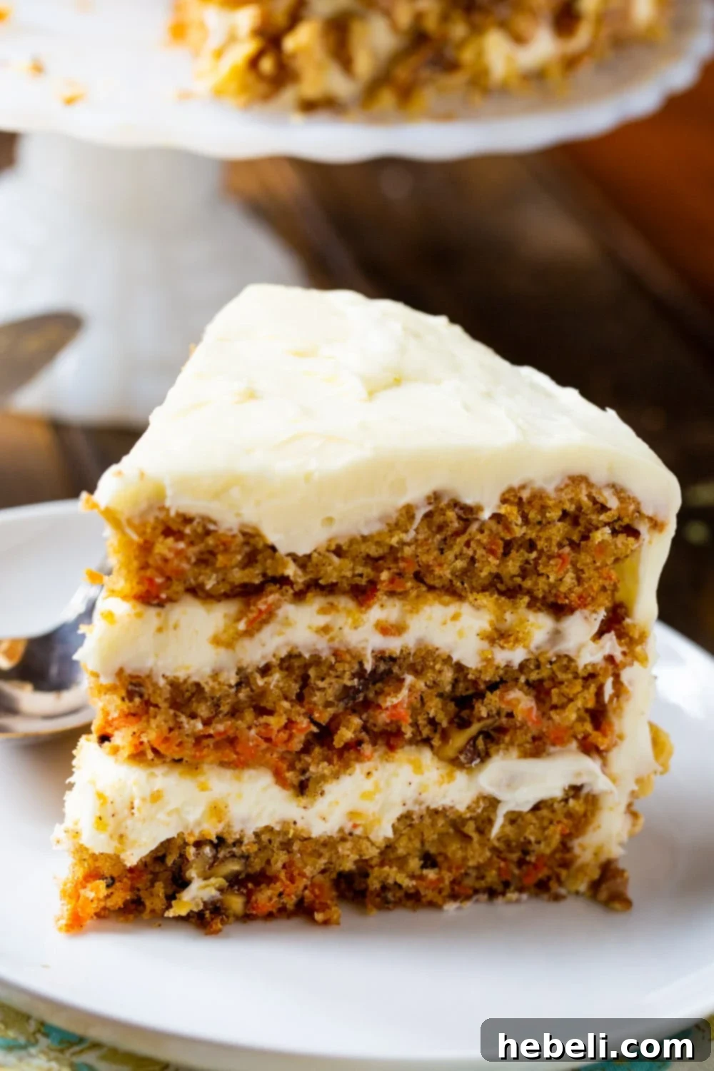 Mama Dip's Legendary Carrot Cake 4 A beautiful slice of Mama Dip's Carrot Cake, complete with generous cream cheese frosting, elegantly presented on a plate.