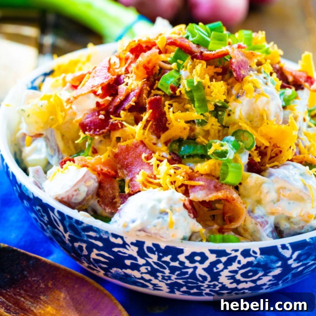 A large, inviting serving bowl filled to the brim with creamy Loaded Ranch Potato Salad, garnished with fresh green onions and crispy crumbled bacon, ready to be enjoyed.