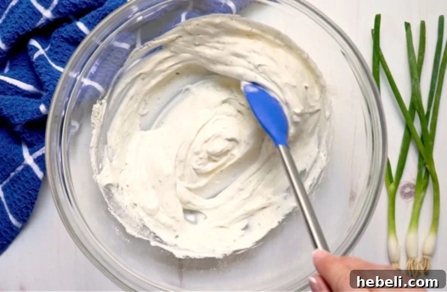 A close-up shot of creamy potato salad dressing being mixed smoothly with a whisk in a bowl.