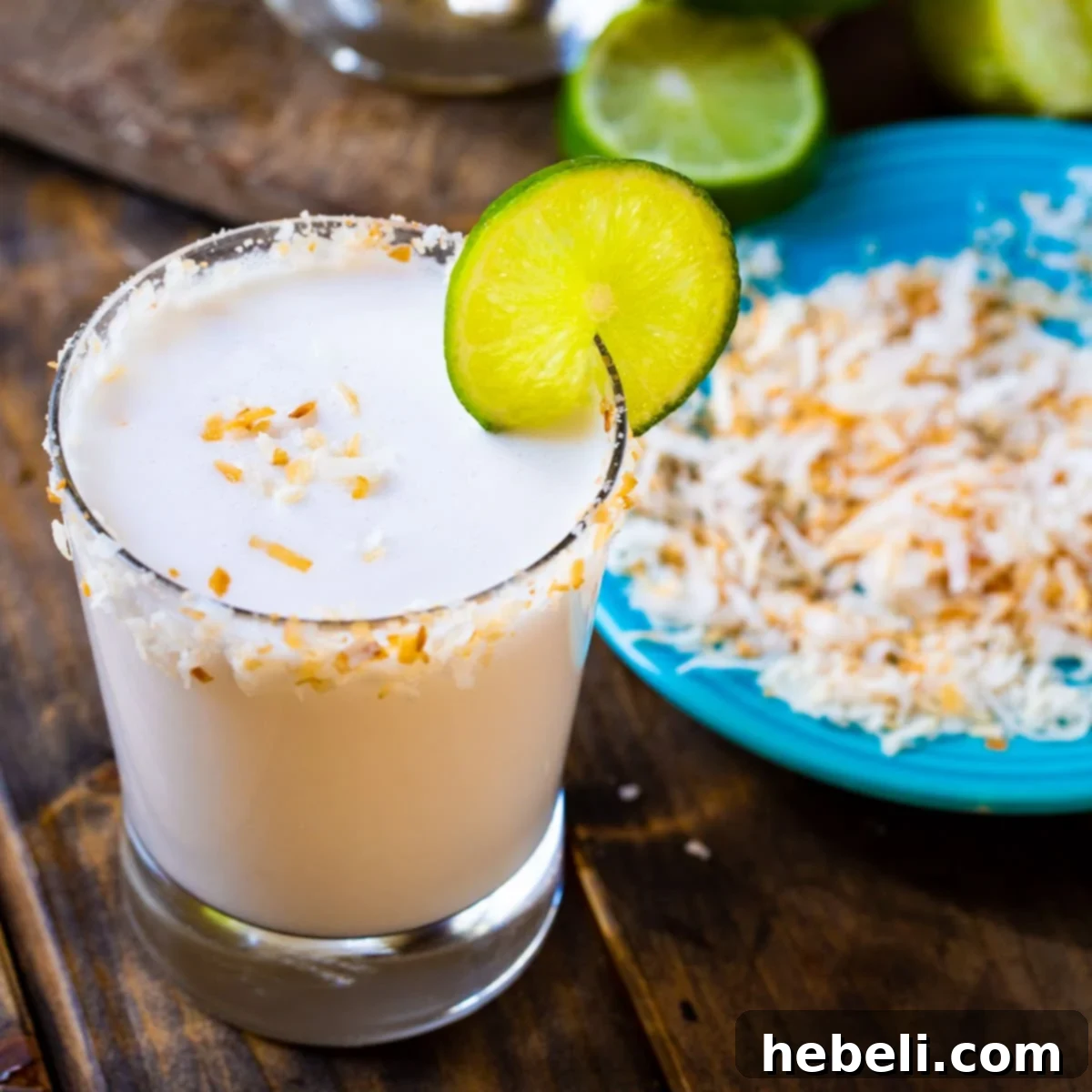 Snow-white Coconut Margarita in a glass with toasted coconut around the rim, evoking a tropical paradise.