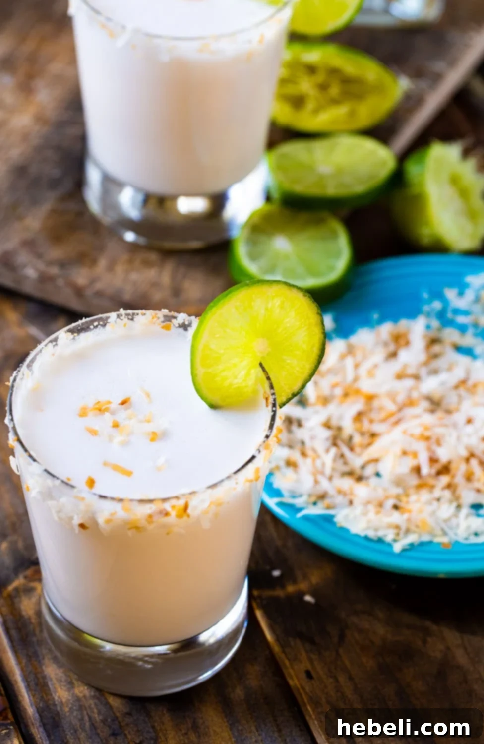Close-up of a Coconut Margarita in a glass, with a plate of toasted coconut for garnish.
