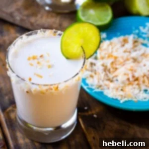 Coconut Margarita in a glass with toasted coconut around rim.