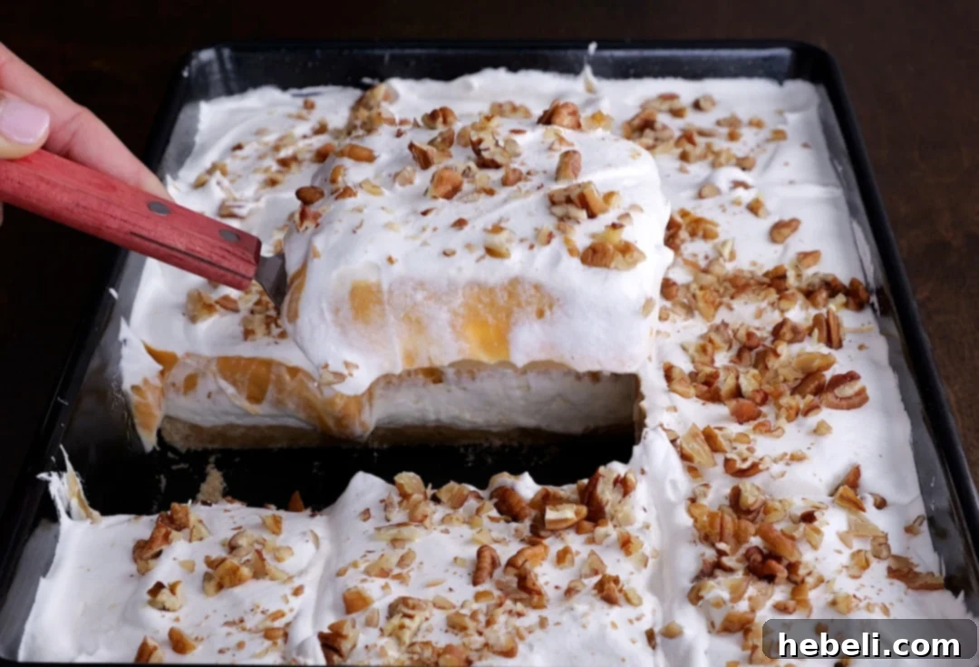 A spatula lifting a perfect piece of Butterscotch Lush from a baking pan, showcasing its distinct layers.