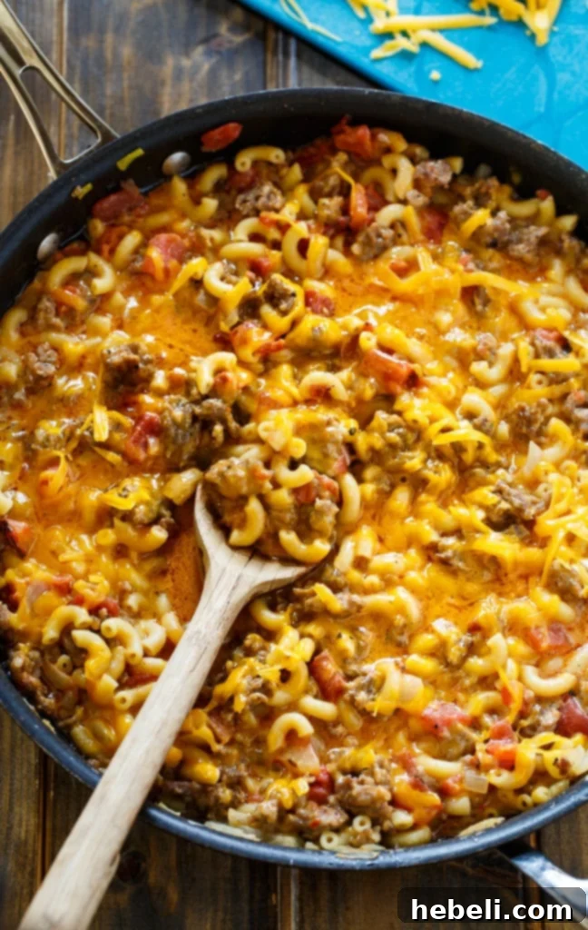 Close-up of creamy stovetop mac and cheese with sausage and tomatoes, highlighting the hearty texture.