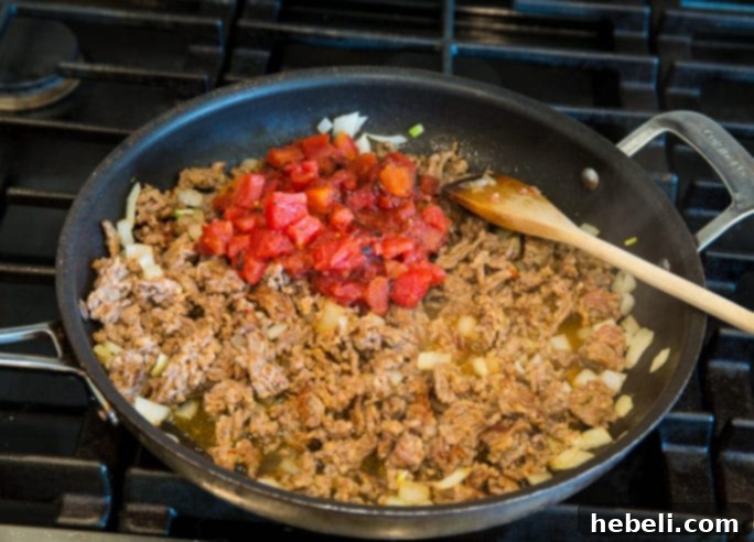Ground Italian sausage and chopped onions browning in a pan for the mac and cheese.