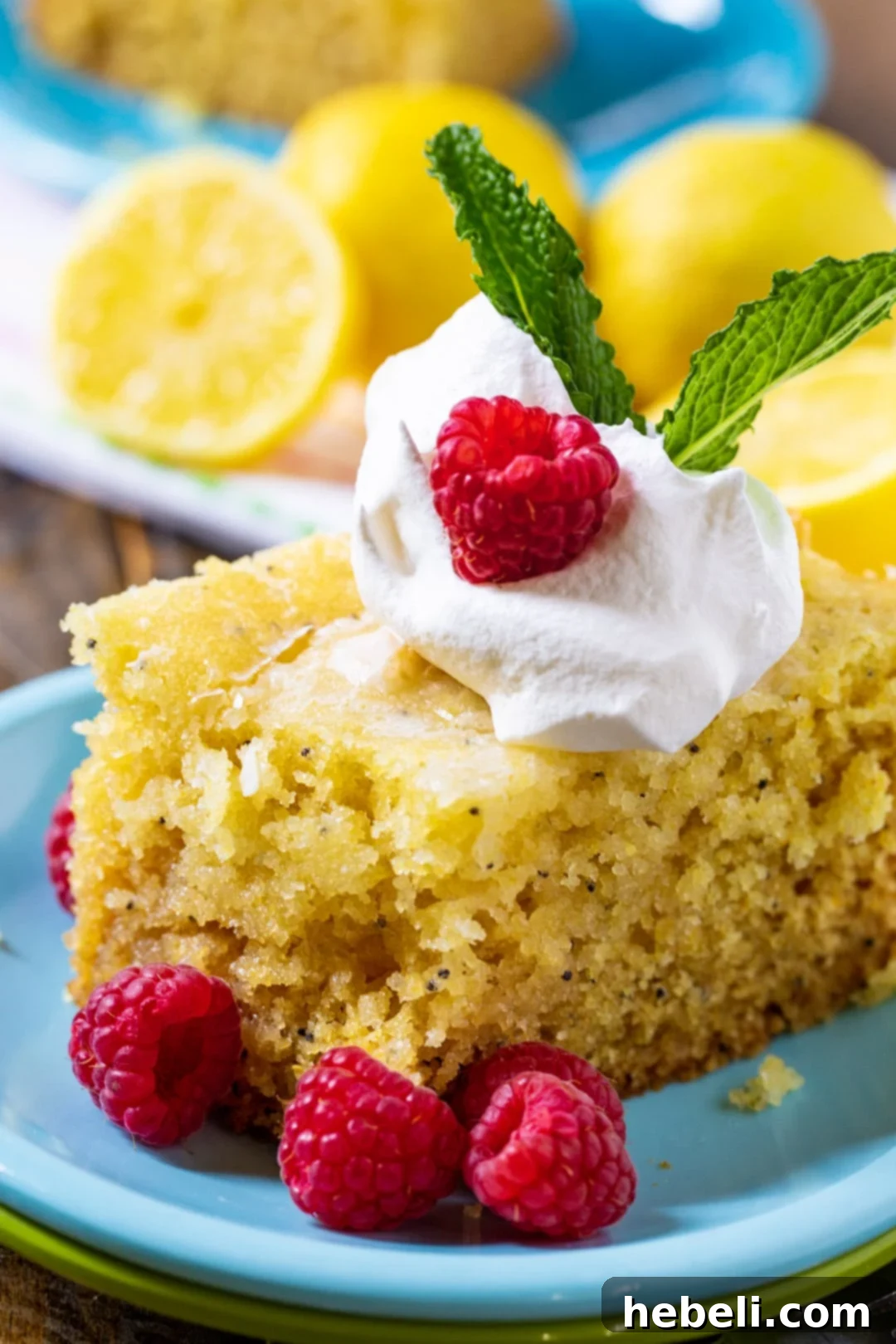 Crock-Pot Lemon Cloud Cake 5 A delicious slice of lemon cake artfully arranged on a blue plate, adorned with vibrant fresh raspberries, ready to be savored.