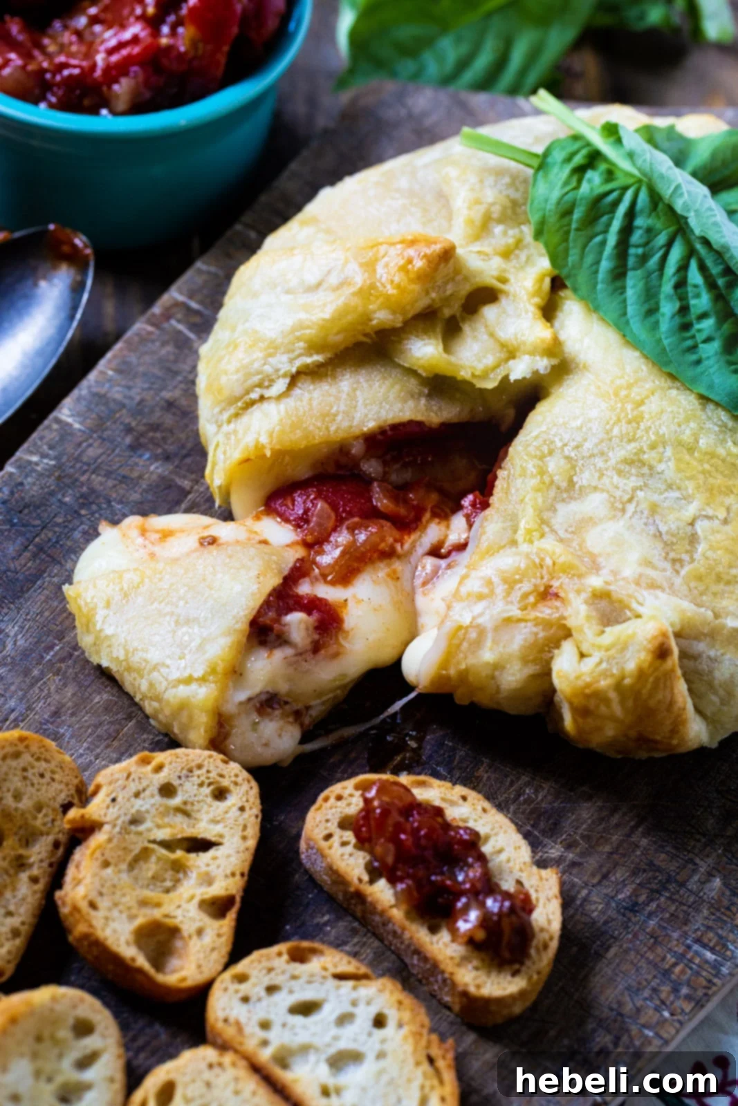 Golden Brie Bake with Tangy Tomato Chutney 3 Wrapped Brie on cutting board with baguette slices.