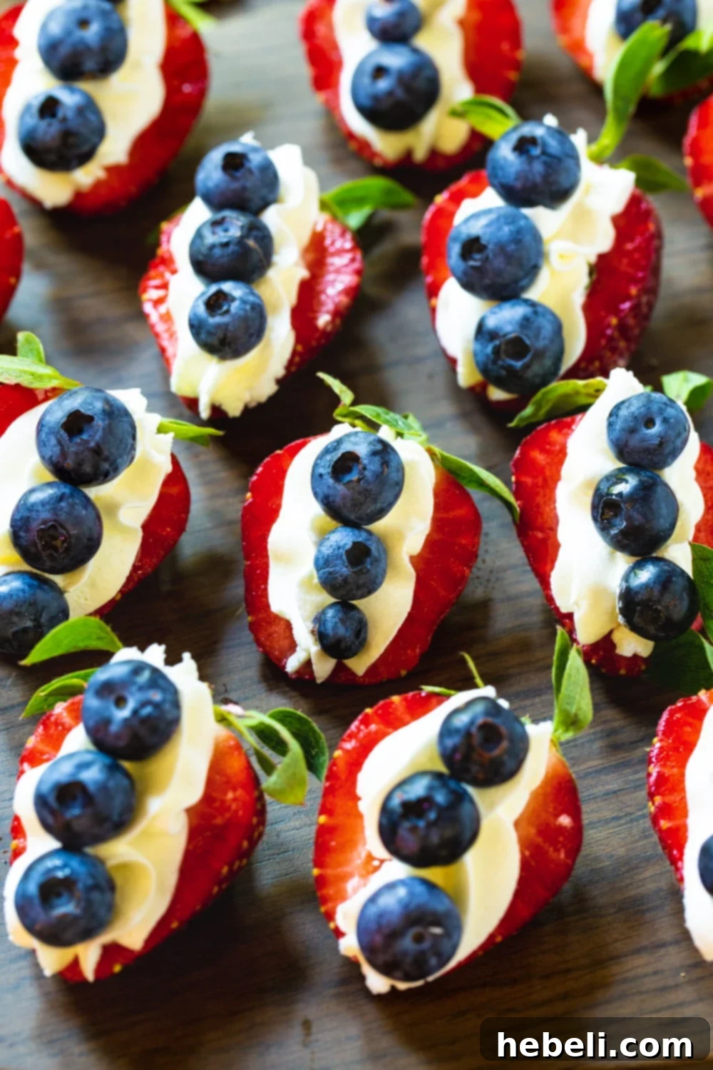 Close-up view of Cheesecake Stuffed Strawberries, each generously topped with fresh blueberries, on a serving platter.