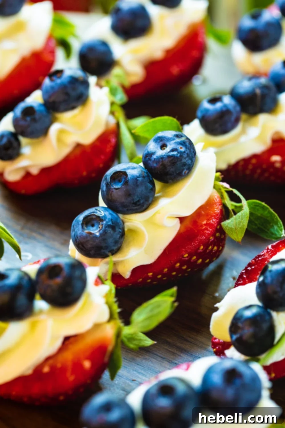A close-up of a platter showcasing multiple Red, White, and Blue Cheesecake Strawberries, highlighting the texture and vibrant colors.