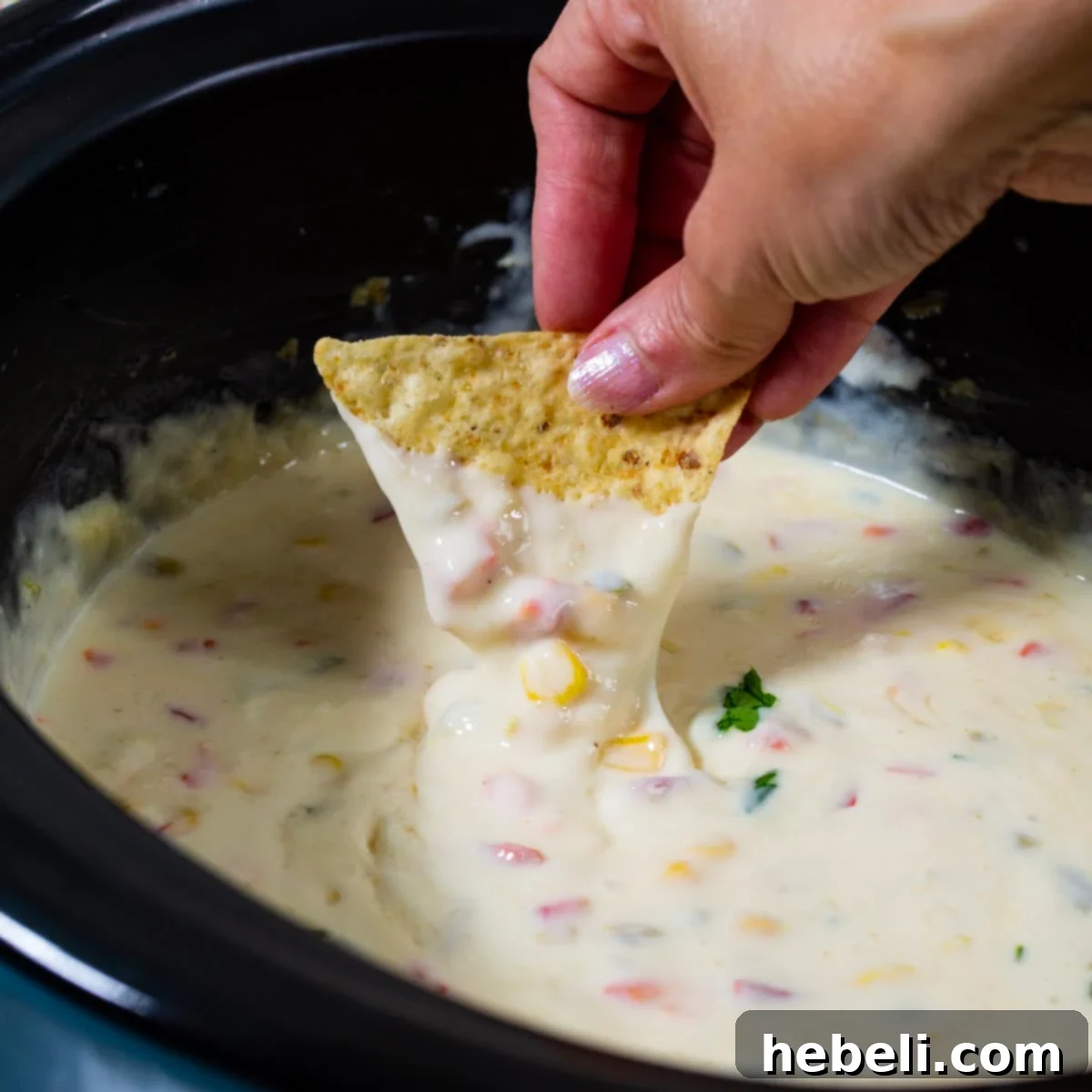 Creamy Crock Pot Queso Blanco 2 Chip dipping into creamy Crock Pot Queso Blanco.