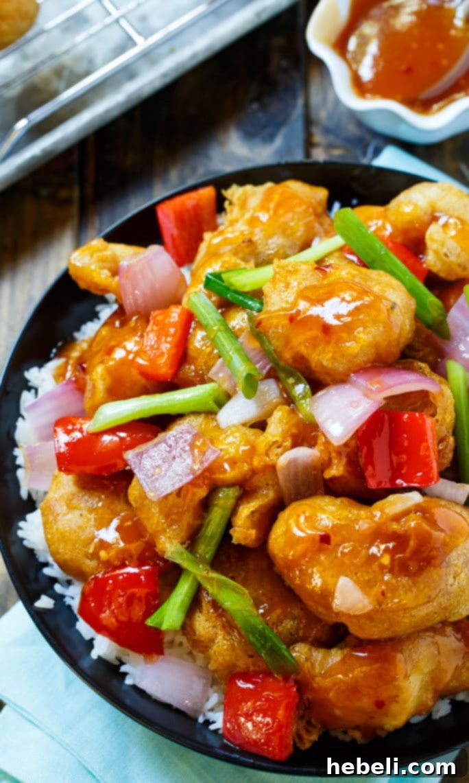 A close-up of homemade Sweet and Sour Chicken, showcasing its golden-brown, crunchy exterior and glistening sauce.