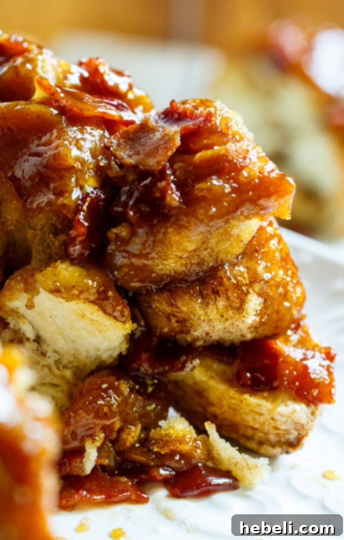 Assembling Bacon Maple Monkey Bread in a Bundt pan with layered biscuit pieces and bacon.