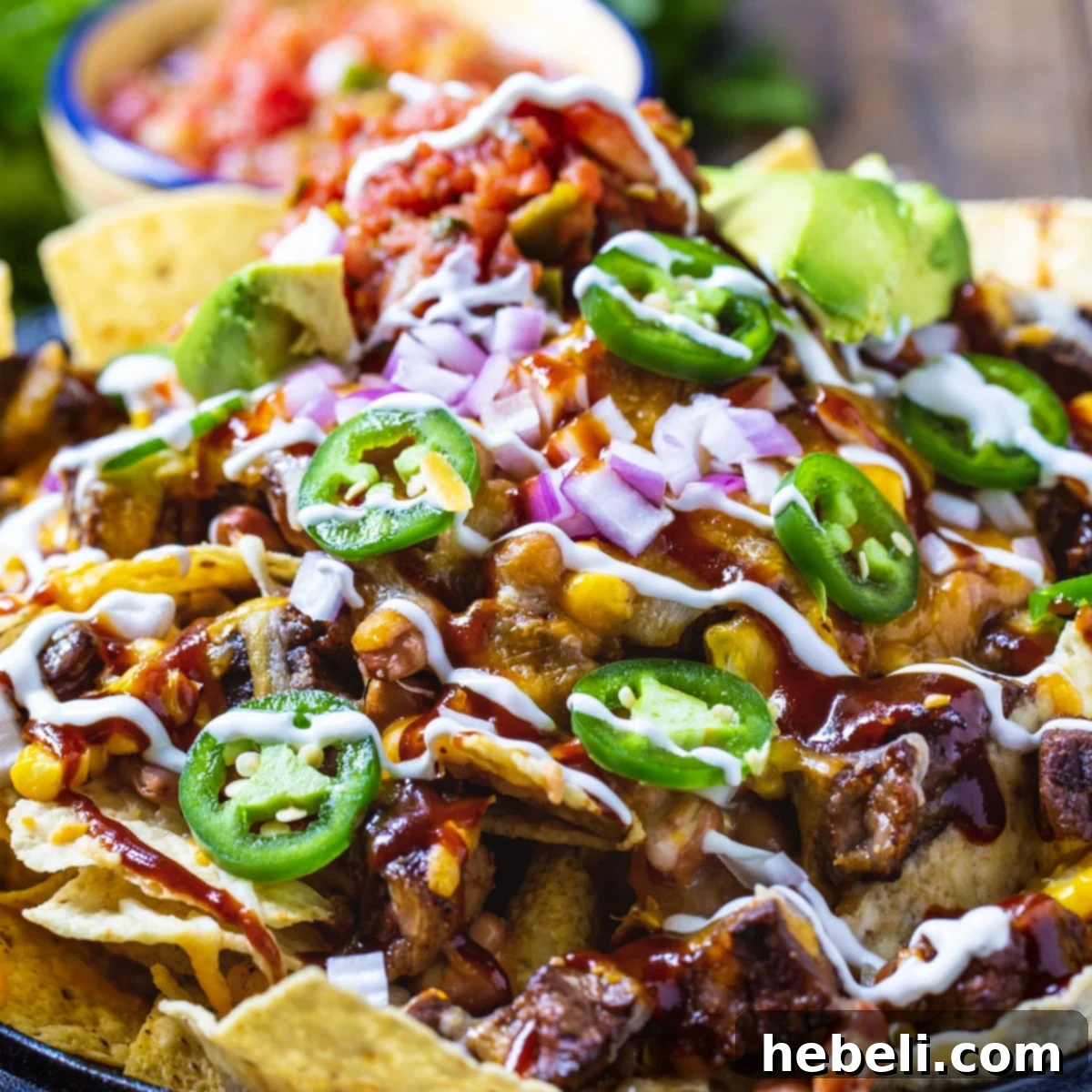 A vibrant platter of BBQ Steak Nachos topped with fresh cilantro and a side of pico de gallo, ready to be enjoyed.