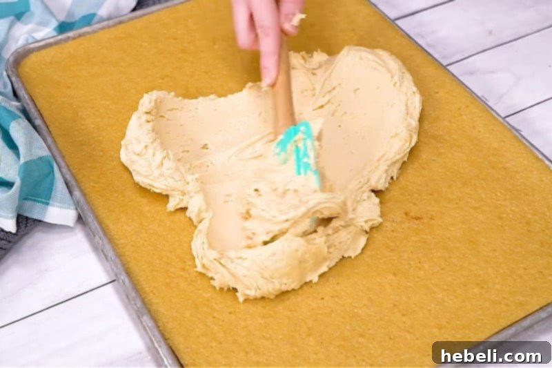 Spreading creamy peanut butter frosting onto a freshly baked sheet cake.