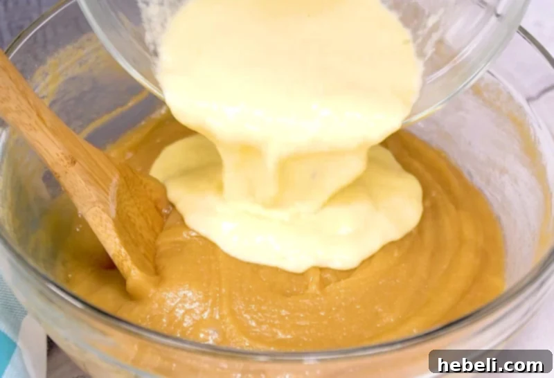 Wet ingredients being added to the cake batter in a mixing bowl.