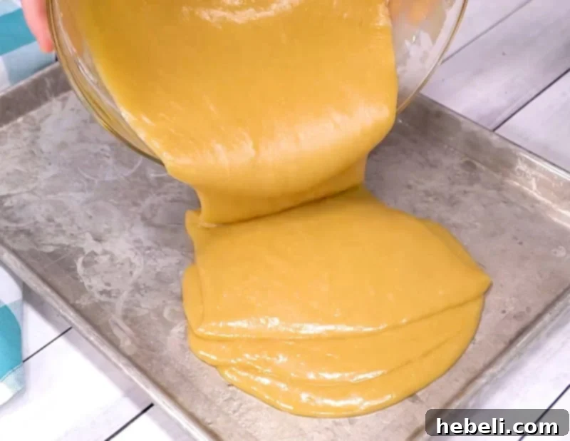 Pouring the cake batter into a prepared sheet pan.