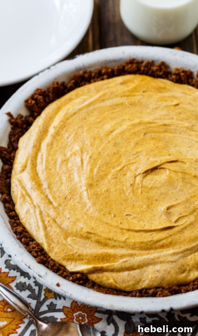 Golden Pumpkin & Mallow Bliss 3 Full Marshmallow Pumpkin Pie sitting on a rustic wooden surface, highlighting its vibrant color and gingersnap crumb texture.