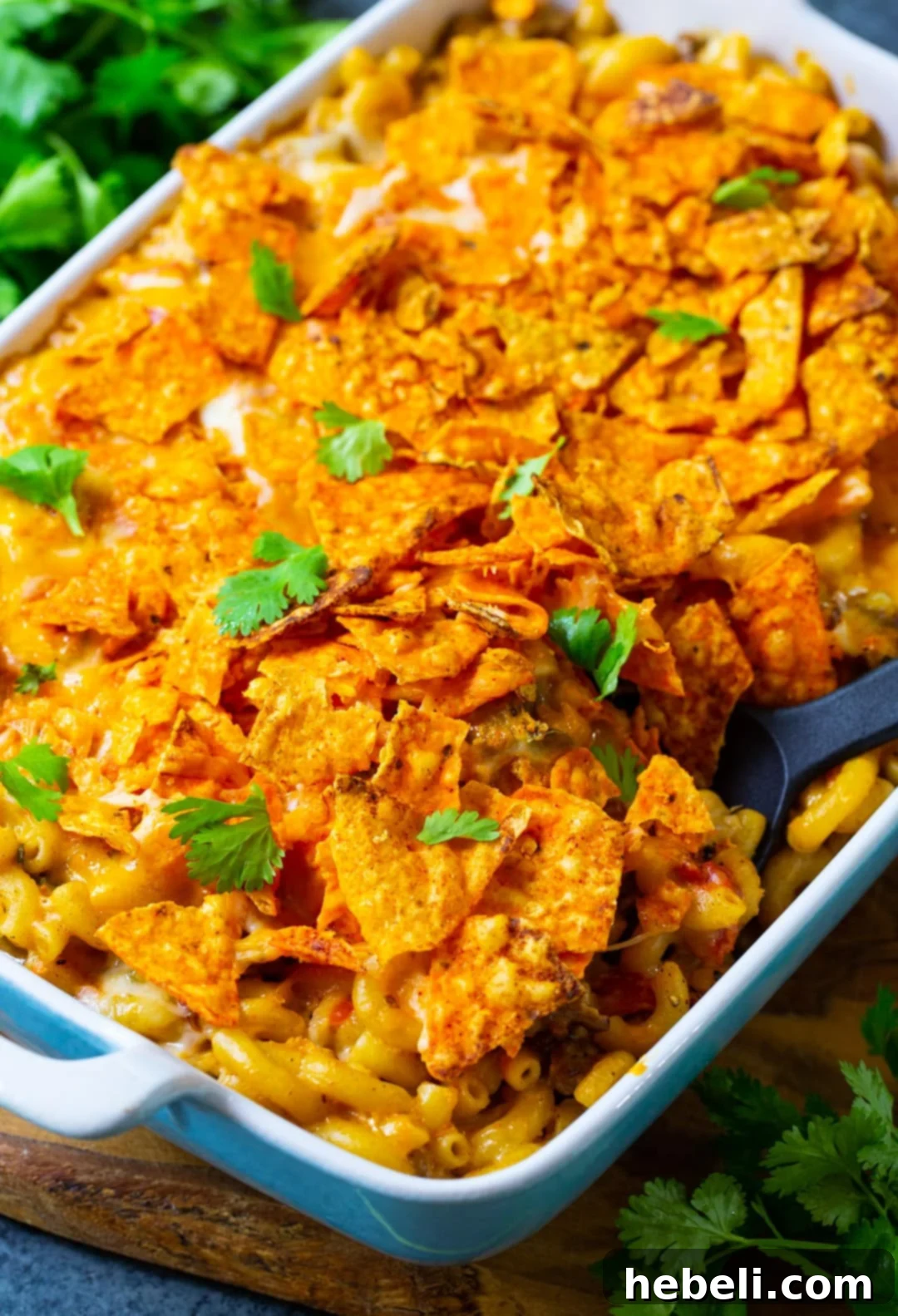 Spoon scooping a generous portion of Nacho Mac and Cheese from the dish.