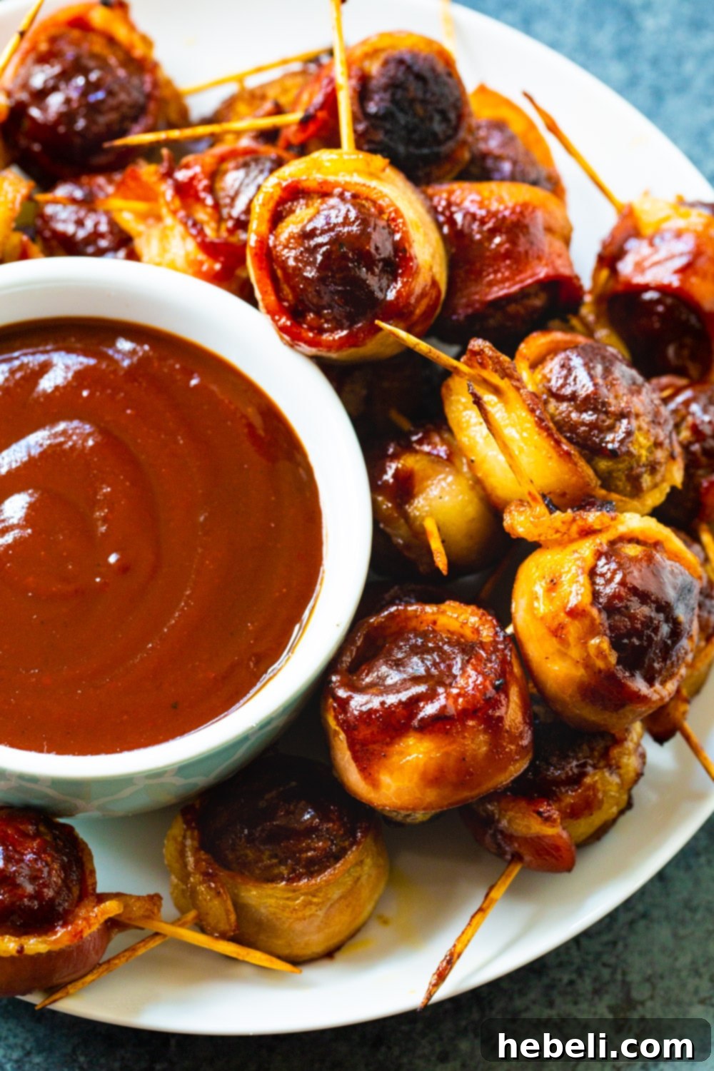 A close-up shot of Barbecue Bacon Meatballs with toothpicks, neatly arranged on a white serving plate.