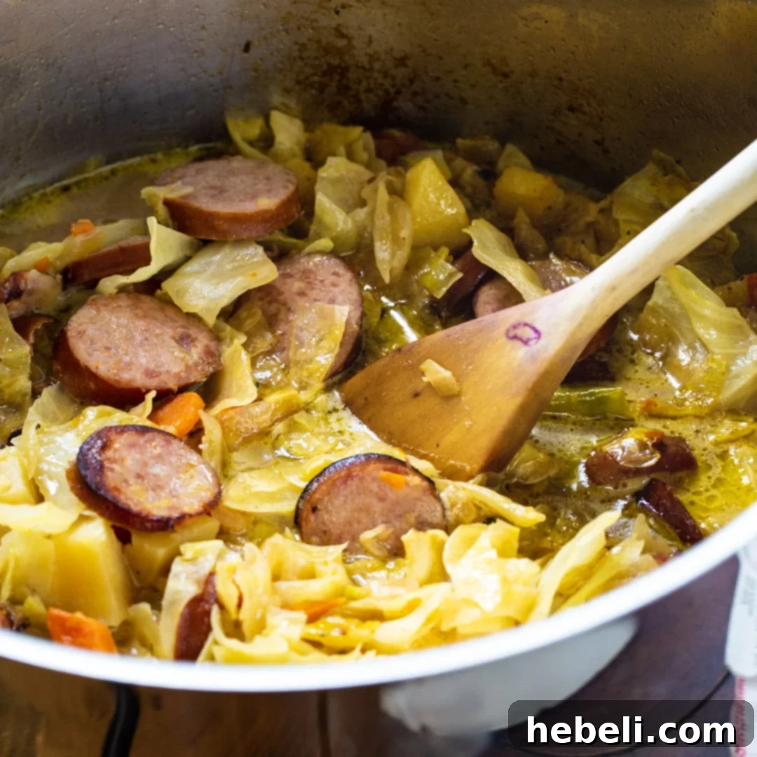 Large pot of Cabbage Soup with Smoked Sausage simmering, steam rising gently.