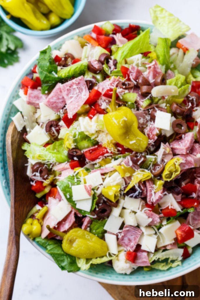 Zesty Italian Deli Salad 4 A large bowl of Muffaletta Salad, generously loaded with a variety of meats, cheeses, and green olives, perfect for a Mardi Gras celebration.