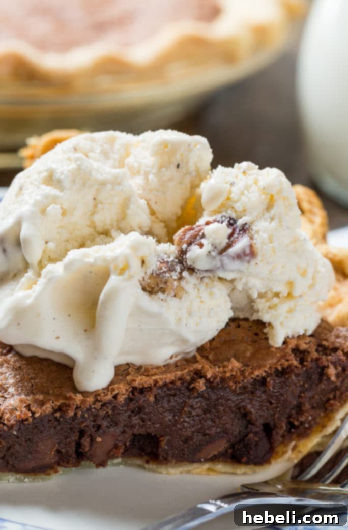 A slice of Brownie Pie with a scoop of ice cream, drizzled with sauce.
