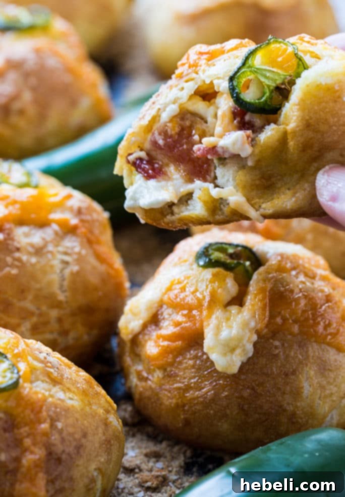 A close-up of a cut Jalapeno Popper Stuffed Pretzel Roll, revealing the warm, melted, cheesy filling inside