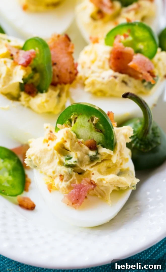Close-up of a tray of Jalapeno Popper Deviled Eggs garnished with bacon and jalapeño slices.