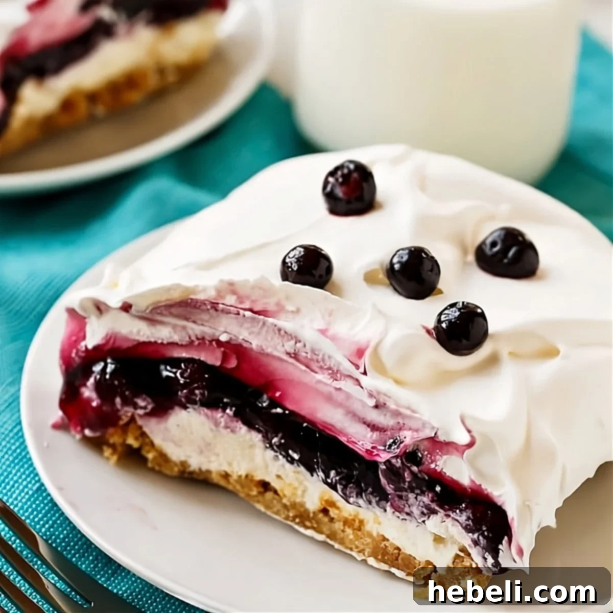 A delectable piece of four-layer Blueberry Lush served on a small white plate, showing its creamy texture and rich blueberry filling.