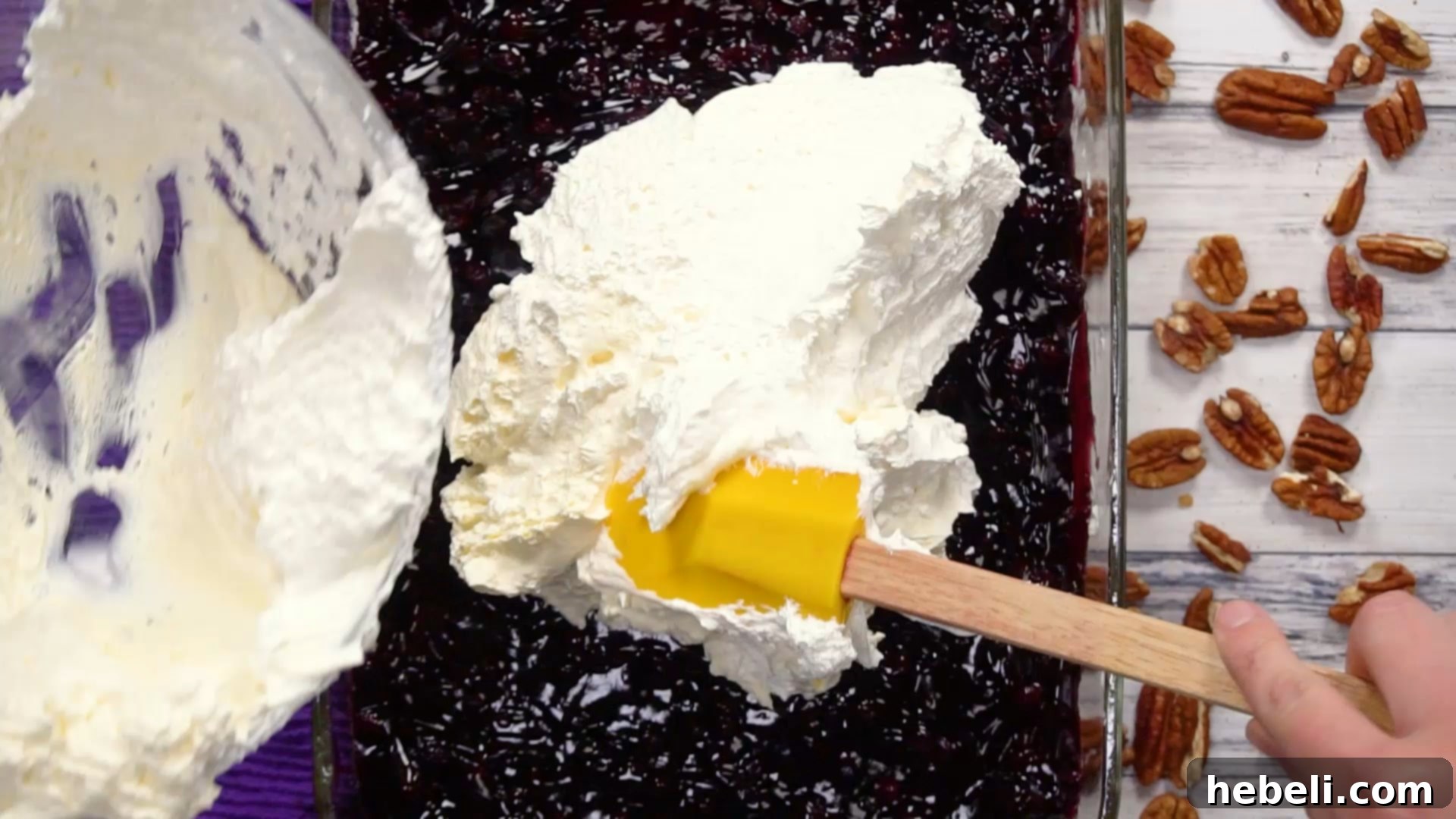 The final step: spreading the creamy whipped topping over the blueberry layer.