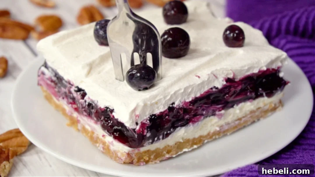 A fork taking a bite out of a piece of blueberry delight, showcasing its creamy layers.