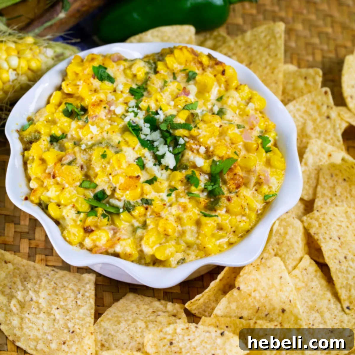 A vibrant bowl of Spicy Mexican Street Corn Dip, generously garnished with fresh cilantro and surrounded by golden, crispy tortilla chips, ready for serving.