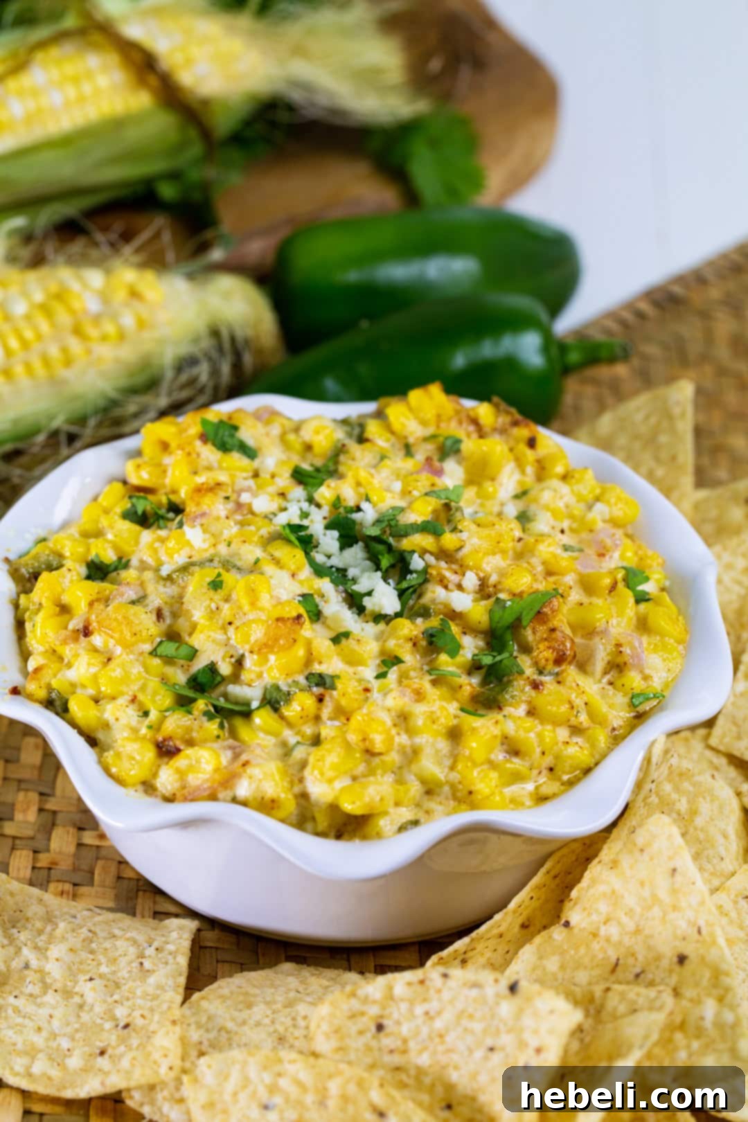 A close-up of a warm and inviting bowl of Mexican Corn Dip, with a golden-brown top, nestled among a variety of crisp tortilla chips, creating a visually appealing appetizer spread.