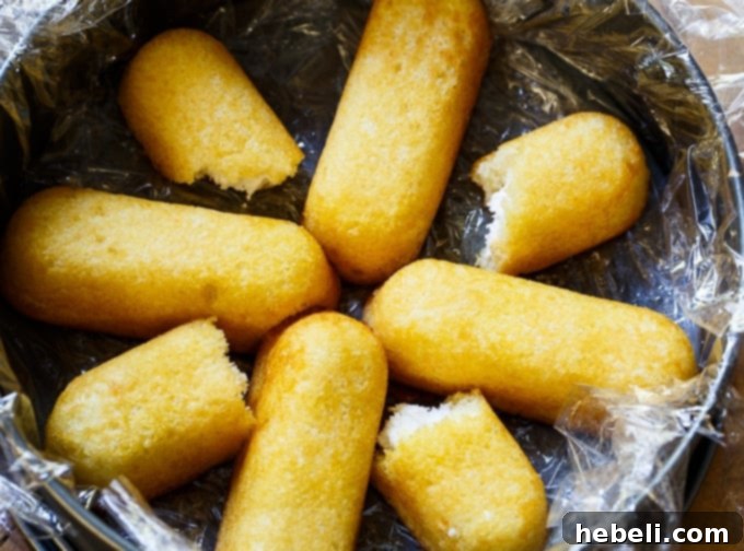 Full view of the Strawberry Twinkie Cake, showing its beautifully arranged layers before slicing, topped with a smooth, white cream cheese mixture and hints of strawberries.