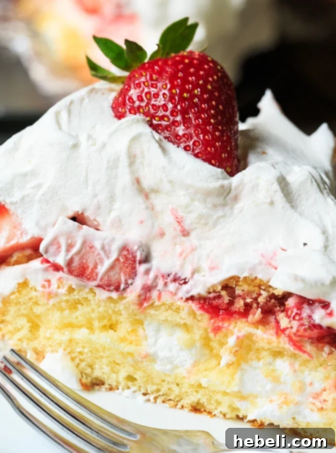 A stunning top-down view of the whole Strawberry Twinkie Cake, beautifully decorated with a smooth layer of whipped cream and fresh strawberry slices on top, ready for serving.